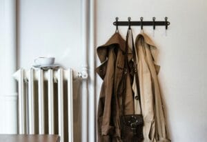 Comfortable home scene with coats on hooks and a cup on a radiator, evoking warmth.